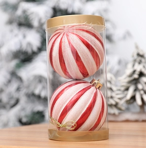 Two red and white striped Christmas balls in transparent packaging on wood