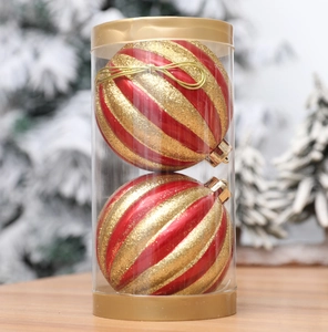 Detail of red and gold striped Christmas pumpkin baubles in a clear cylinder package
