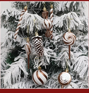 Close-up of bronze and white candy-shaped Christmas ornaments hanging on a snowy tree