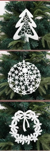 Adornos navideños blancos escarchados con copos y coronas en ramas de pino