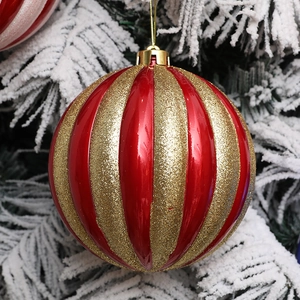 15 cm Weihnachts-Kürbisball in Rot und Gold mit Glitzerstreifen auf verschneitem Kiefernzweig