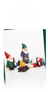 Macro detail of three resin gnome figurines with a miniature campfire garden ornament