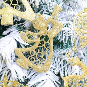 Adornos navideños dorados con purpurina con renos y copos colgados en un árbol nevado
