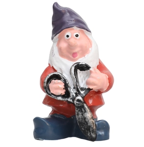 Close-up of a fairy garden gnome figurine holding large black scissors with purple hat