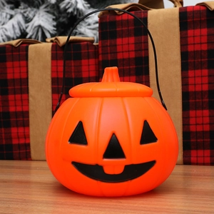 Classic Halloween pumpkin candy bucket with black handle on a festive wooden tabletop