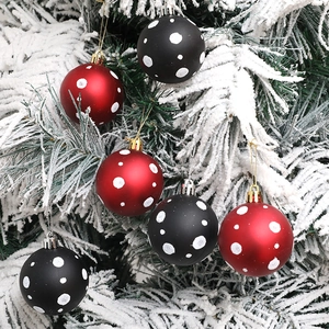 Bolas de Navidad rojas y negras mates con lunares blancos en ramas nevadas