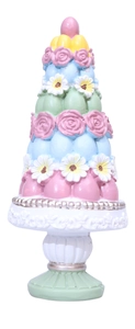 Detail of stacked colorful Easter eggs and delicate resin flowers on an ornate white base