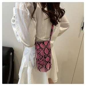 Close-up of pink and black snake print mini bag with long fringe tassels and leather texture