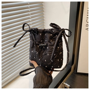 Detail of black quilted shoulder bag featuring white rabbit prints and cute bow accents