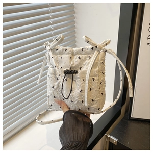 Close-up of white quilted crossbody bag featuring elegant black bow floral print details