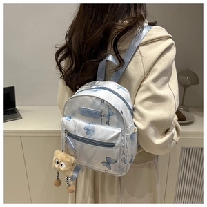 Detail of cream mini backpack with blue butterfly prints and plush bear pendant
