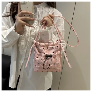 Detail of pink quilted bubble fabric crossbody bag with bow patterns and drawstring closure