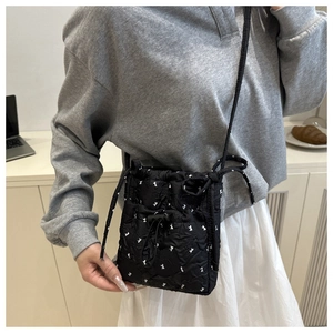 Detail of black quilted bubble fabric shoulder bag with white rabbit silhouette patterns