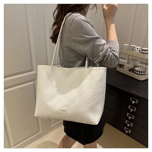 Detailed close-up of white woven tote bag texture with FASHION leather label and strap