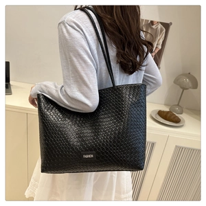 Detailed close-up of woven texture and fashion label on a large black tote bag