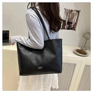 Detail view of black woven leather tote bag with long straps for office commute fashion