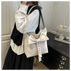 Detail of elegant cream shoulder bag with large bow decoration and silver studs