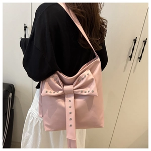 Vue détaillée du sac cabas rose en similicuir avec nœud et clous porté par un mannequin