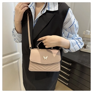 Model wearing a nude pink crossbody bag with white butterfly buckle and V-shaped quilting