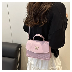 Detail of light purple handbag featuring V-quilted texture and butterfly buckle