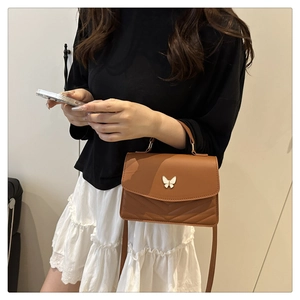 Brown mini crossbody bag featuring a silver butterfly buckle and stylish V-quilted pattern