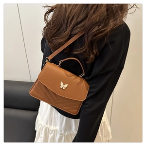 Close-up of brown PU leather bag with metal butterfly buckle and V-shaped stitching detail