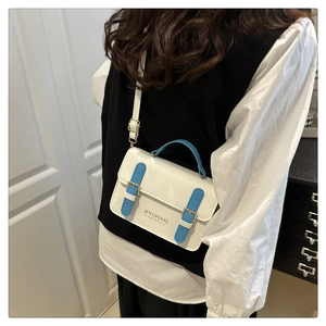 Detail view of small cream crossbody bag with blue straps shown on a female model