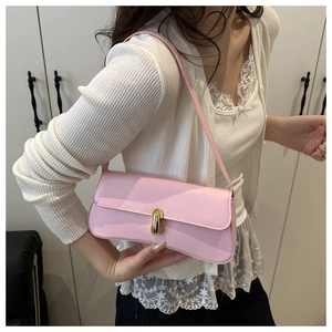 Close-up of a pink baguette bag with golden metal twist lock and smooth leather texture
