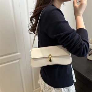 Minimalist beige leather baguette bag with gold buckle shown on woman shoulder