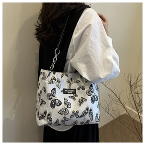 Détail du sac cabas imprimé papillon avec bandoulière chaîne porté par un mannequin