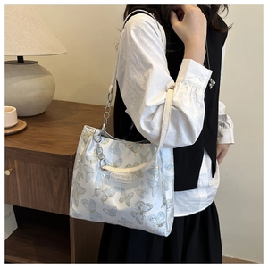 Détail du sac blanc avec broderie exquise de papillons bleus et dorés et sangle en chaîne