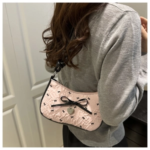 Close-up of pink crescent bag with black bow prints, pleated texture and metal heart charm