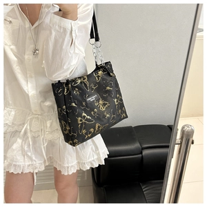 Détail du sac cabas noir avec motifs papillons dorés et bandoulière en chaîne