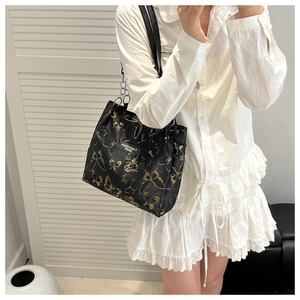 Détail d'un sac d'épaule en nylon noir avec motifs papillons dorés et bandoulière chaîne