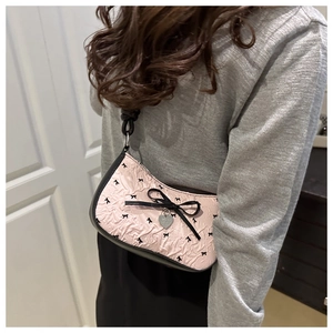Détail du sac bandoulière rose à nœuds noirs et pendentif en forme de cœur argenté