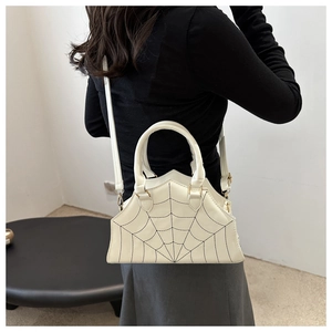 Detailed back view of white handbag featuring unique black spiderweb stitching and long strap