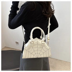 Detail of white PU handbag featuring black spider web embroidery and gold hardware