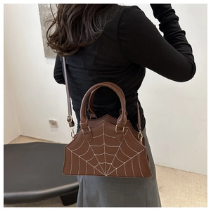 Detail of dark brown shell bag with white spiderweb stitching and leather texture
