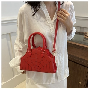 Detail of red shell-shaped bag with black spider web stitching worn by a model
