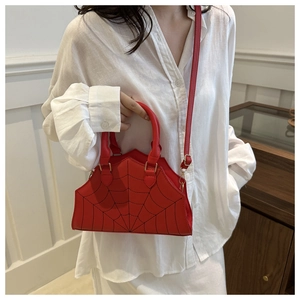 Detail of red spider web crossbody bag with golden hardware and adjustable strap