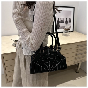 Detail of black leather shell bag with white spider web embroidery and gold hardware