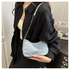 Détail du sac demi-lune en denim bleu clair avec chaîne argentée porté à l'épaule