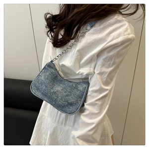 Détail du sac sous le bras en denim bleu clair avec fini pailleté argenté et chaîne