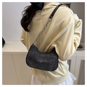 Détail du sac hobo noir à motif strass avec bandoulière chaîne porté à l'épaule