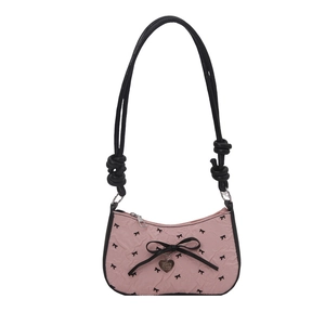 Pink crescent underarm bag with black bow embroidery and heart pendant on white background