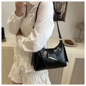 Gros plan du sac à bandoulière noir brillant avec une boucle en métal argenté pointu