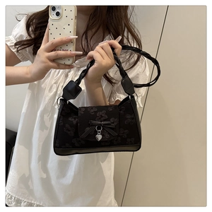 Detail der schwarzen Cloud-Tasche mit Blumenstickerei, Schleife und geflochtenem Griff