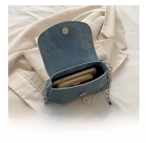 Detail showing the spacious interior of a blue denim shoulder bag with a phone and wallet