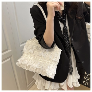 Close-up of white lace layered ruffle tote bag styled with a professional black blazer