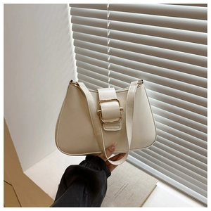 Close-up of cream shoulder bag featuring a large gold square buckle and textured faux leather